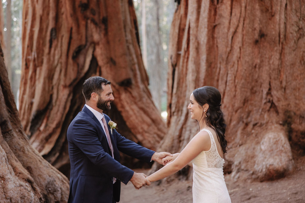 A bride in a white gown holds a bouquet while standing in front of large redwood trees 
Top 5 reasons to elope in sequoia national park