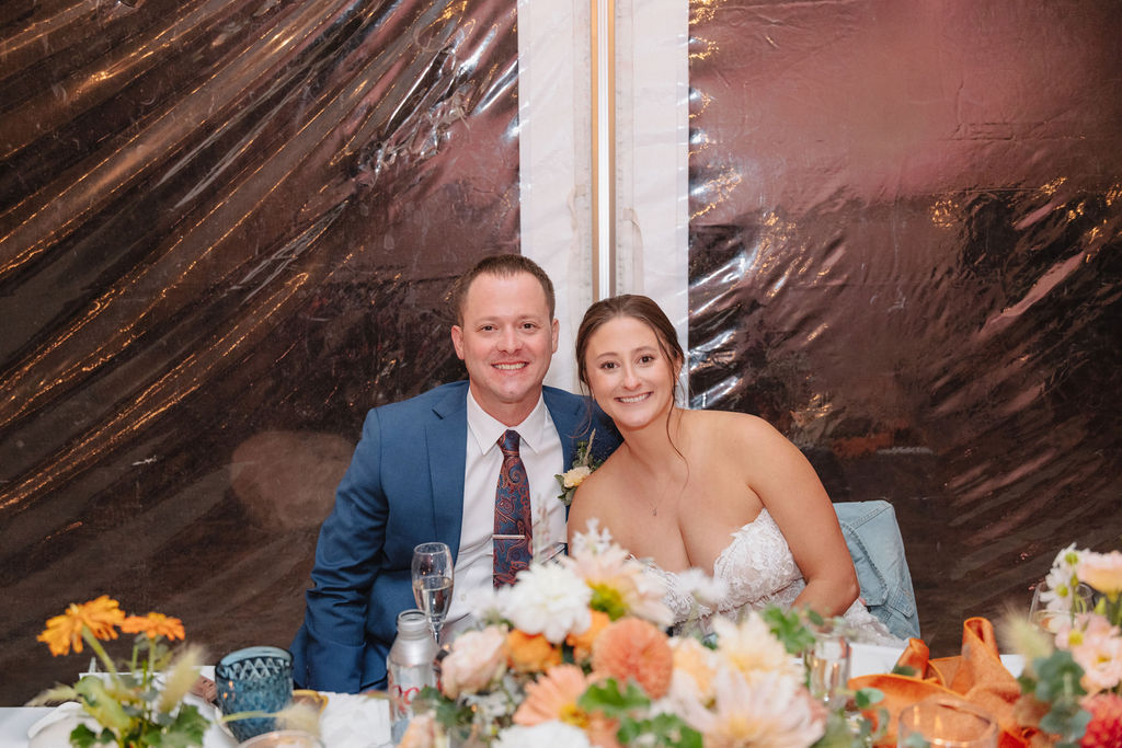 A person in a gray suit gives a toast to a seated couple at a decorated table with flowers and candles at a wedding at sierra star golf course