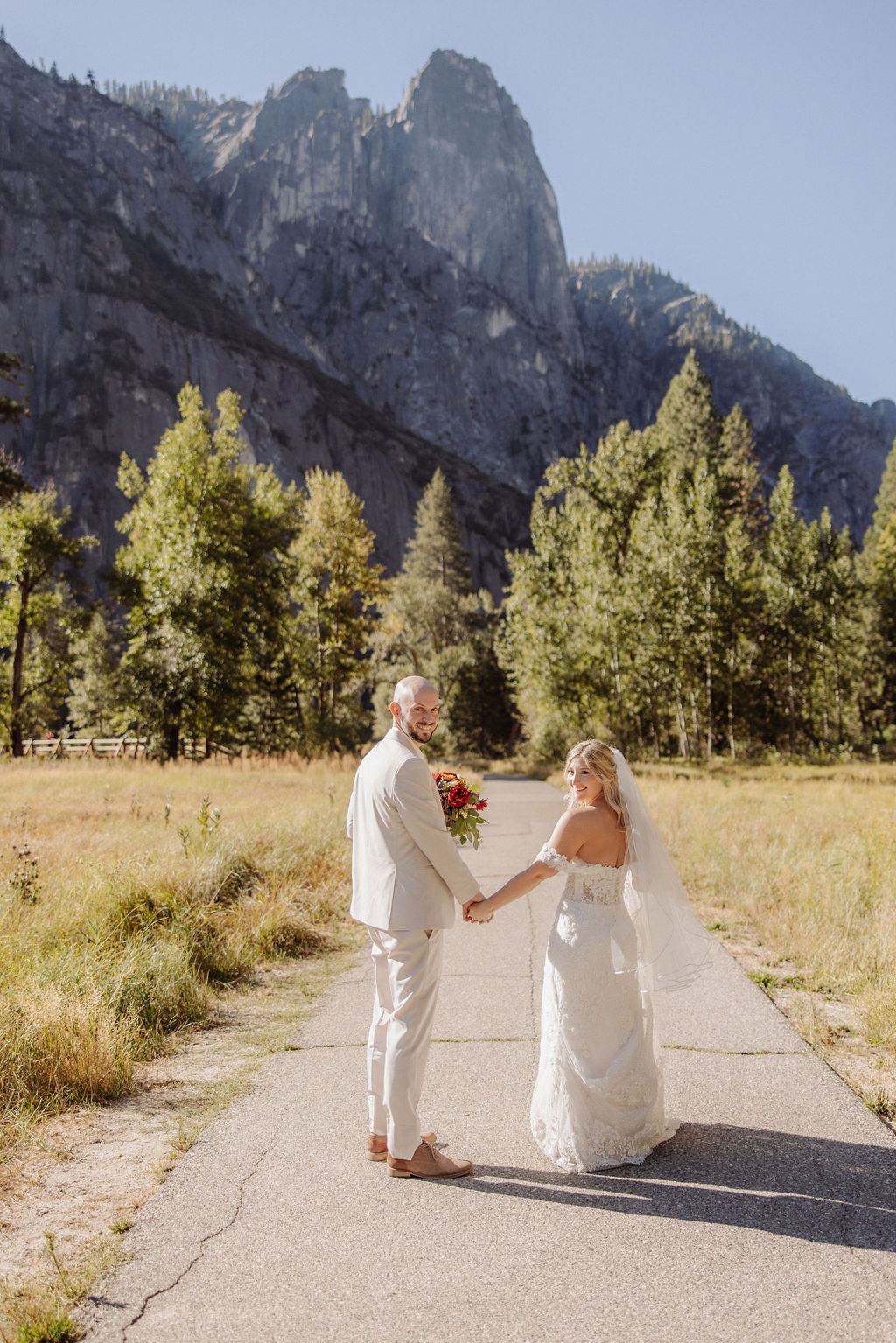 Bride and groom embracing on a rocky hilltop, with sunlight in the background and a mountain view for a sustainable wedding tips