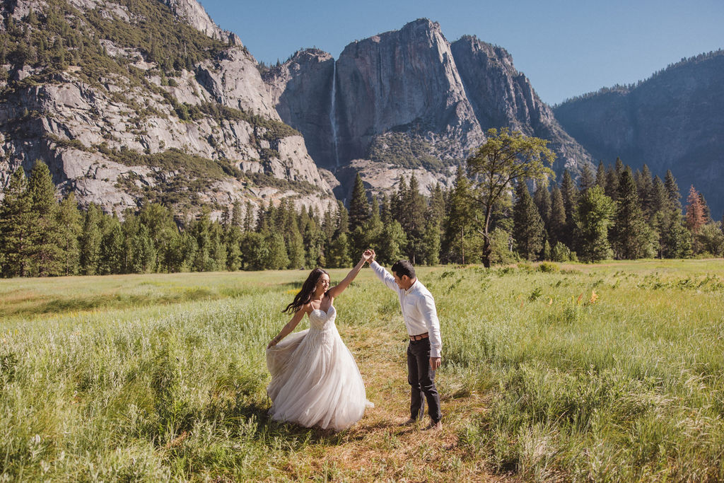 couple takes photos at their yosemite elopement on a field The Best Time for a Yosemite Elopement