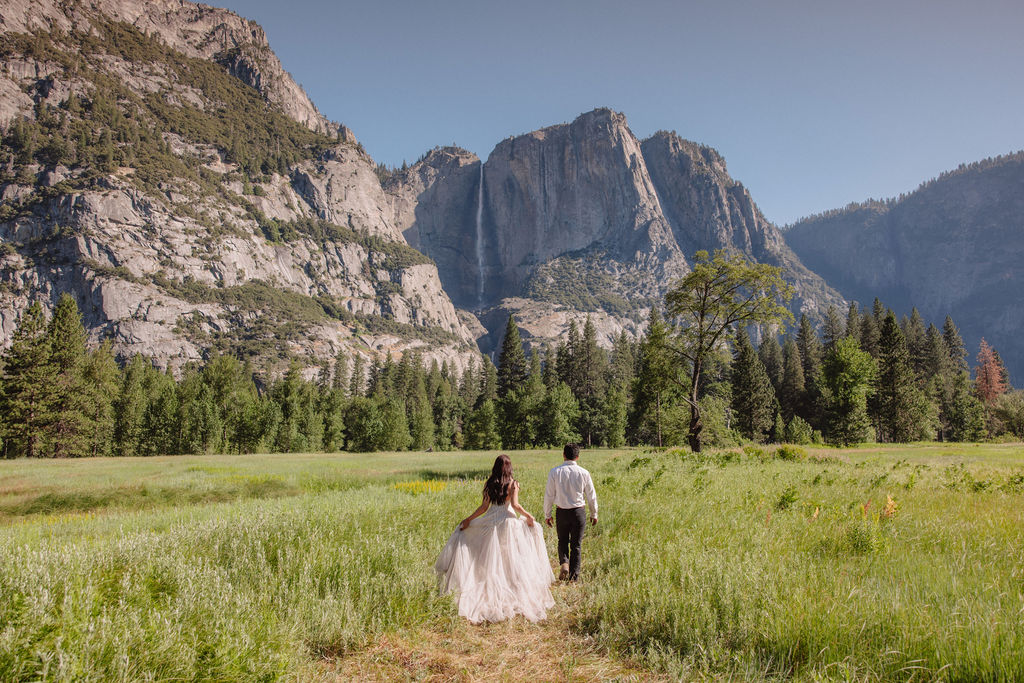 couple takes photos at their yosemite elopement on a field The Best Time for a Yosemite Elopement