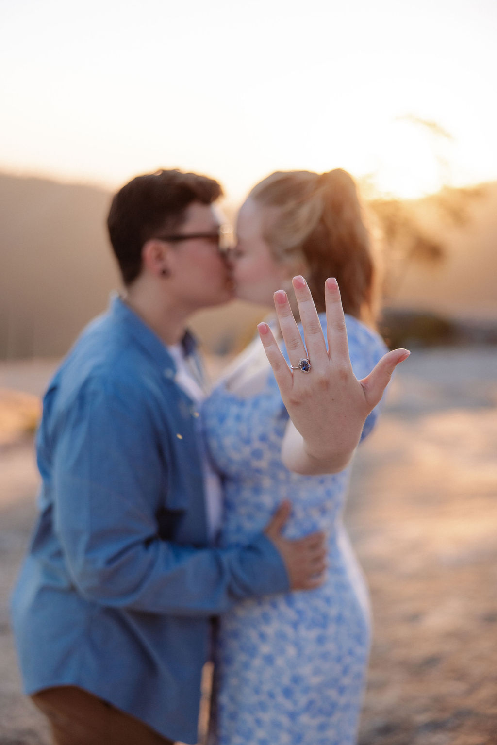 A couple holding hands walks on a rocky surface overlooking a scenic mountain landscape at sunset for their sequoia national park engagement photos