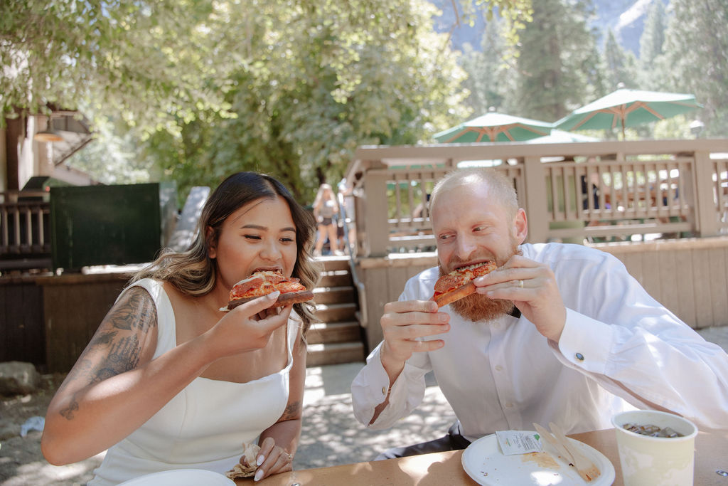 A woman and a man sit at an outdoor table sharing a pizza, each reaching for a slice. Two large drinks are on the table in front of them for a glacier point elopement 