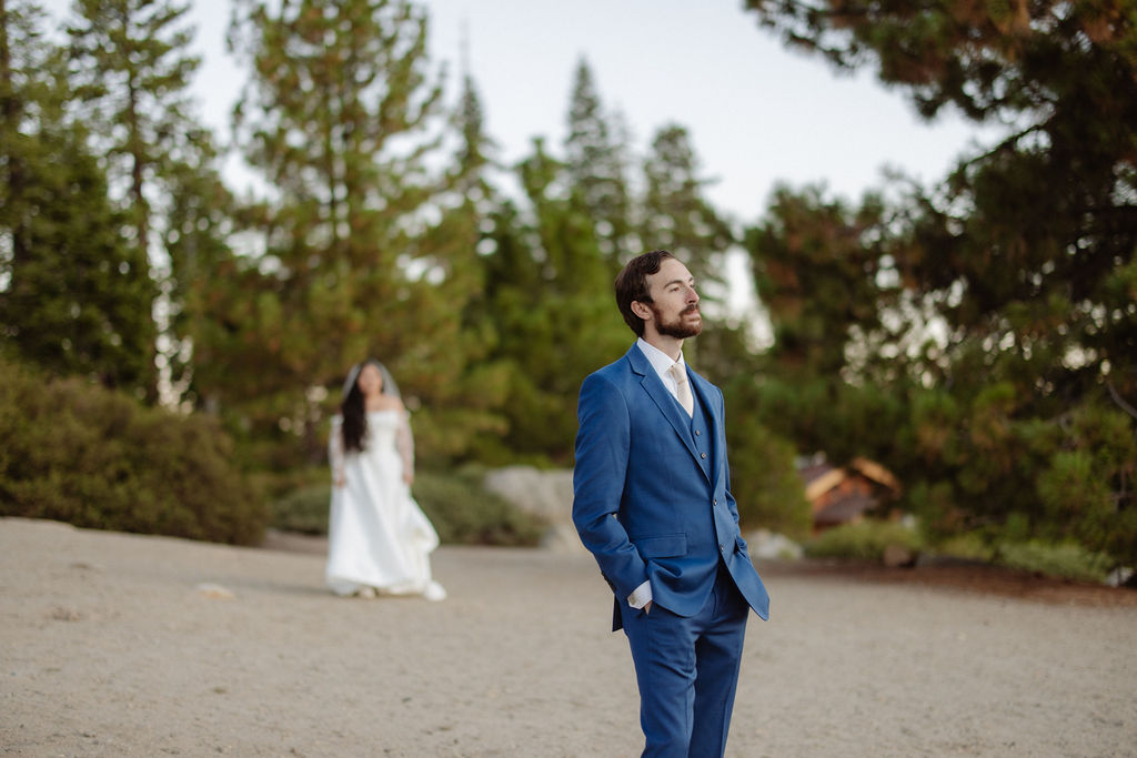 A bride and groom embrace outdoors with mountains and trees in the background, including a prominent granite peak for a wedding at yosemite