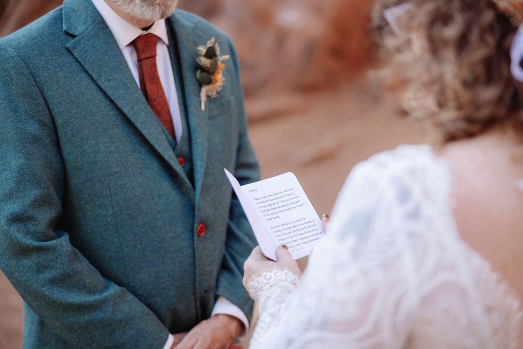 A couple stands with an officiant among giant redwood trees during a wedding ceremony in a forest setting taken. y a sequoia elopement photographer