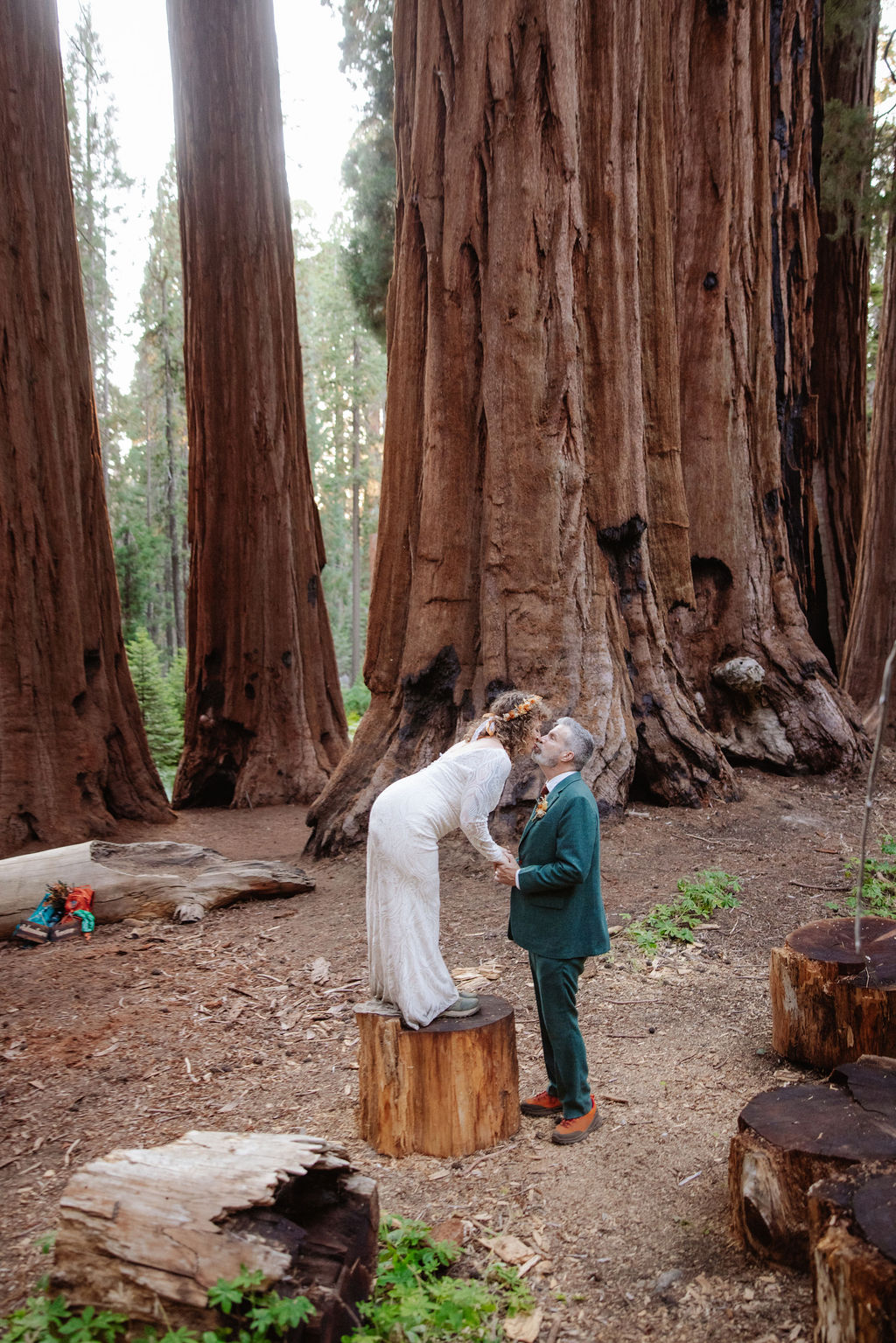 A couple stands embraced on a forest path between towering redwood trees taken by a sequoia elopement photographer