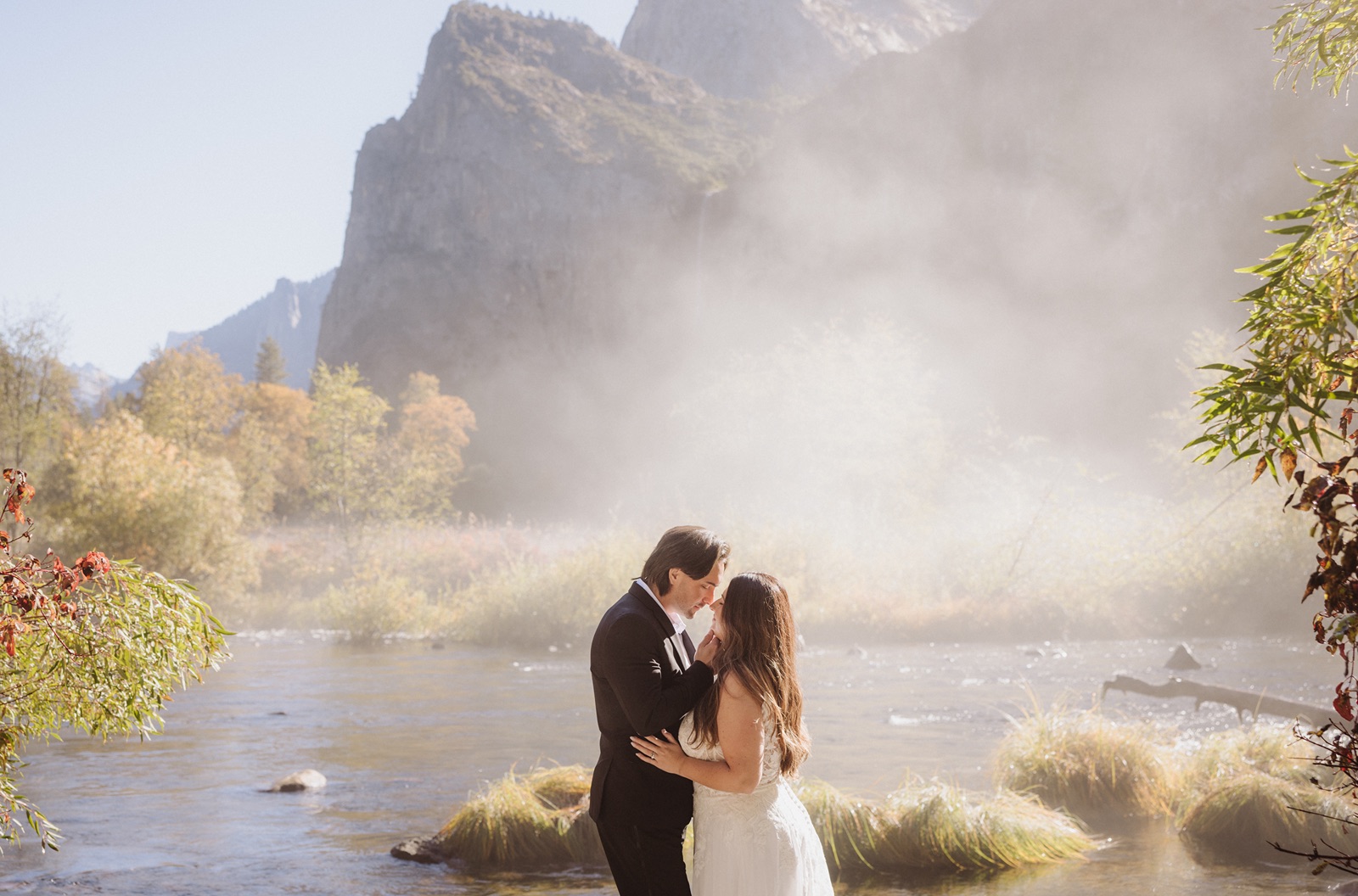 Bride and groom pose with epic cloudy Yosemite backdrop