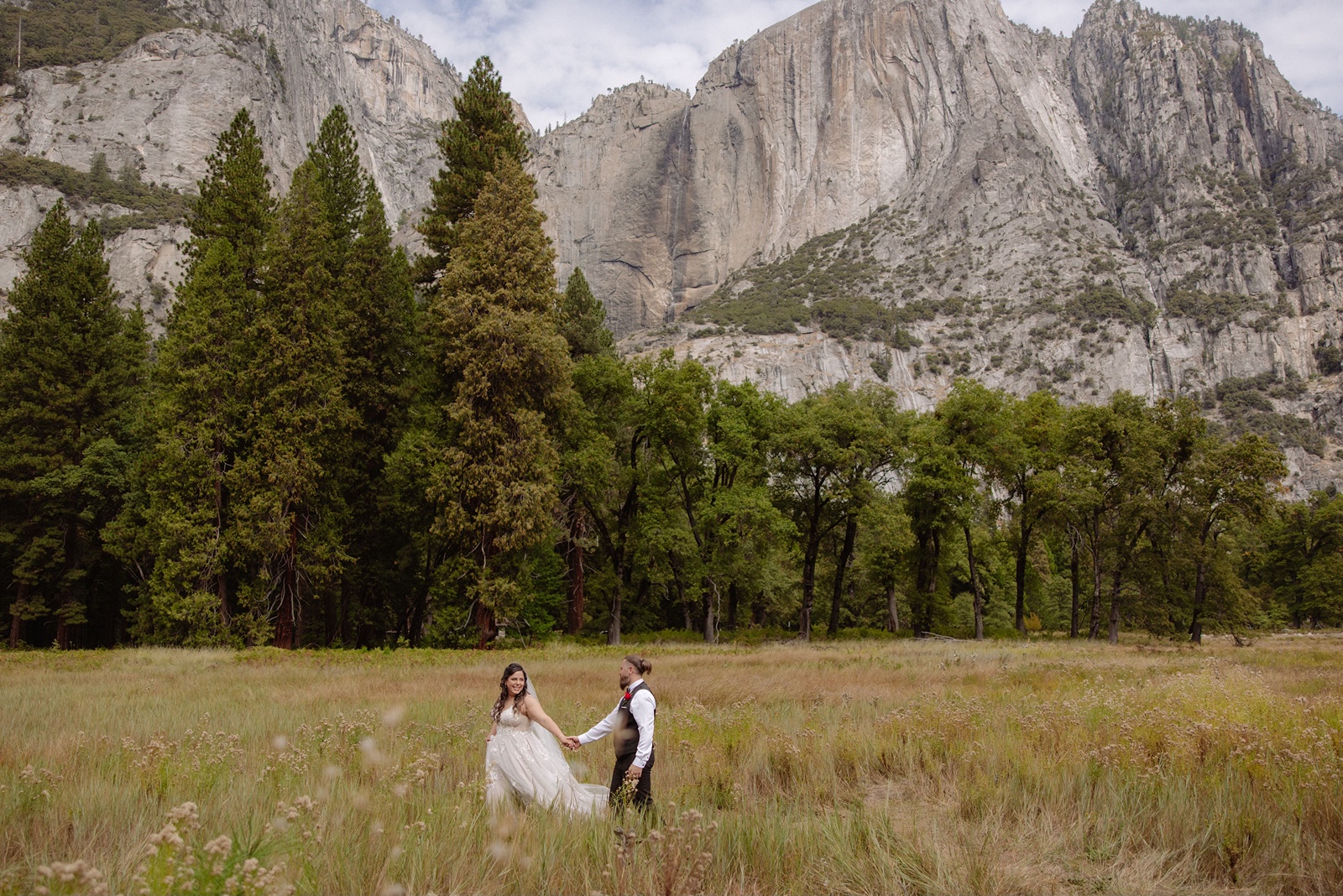 Bride and groom hold hands in Cooks Meadow in Yosemite