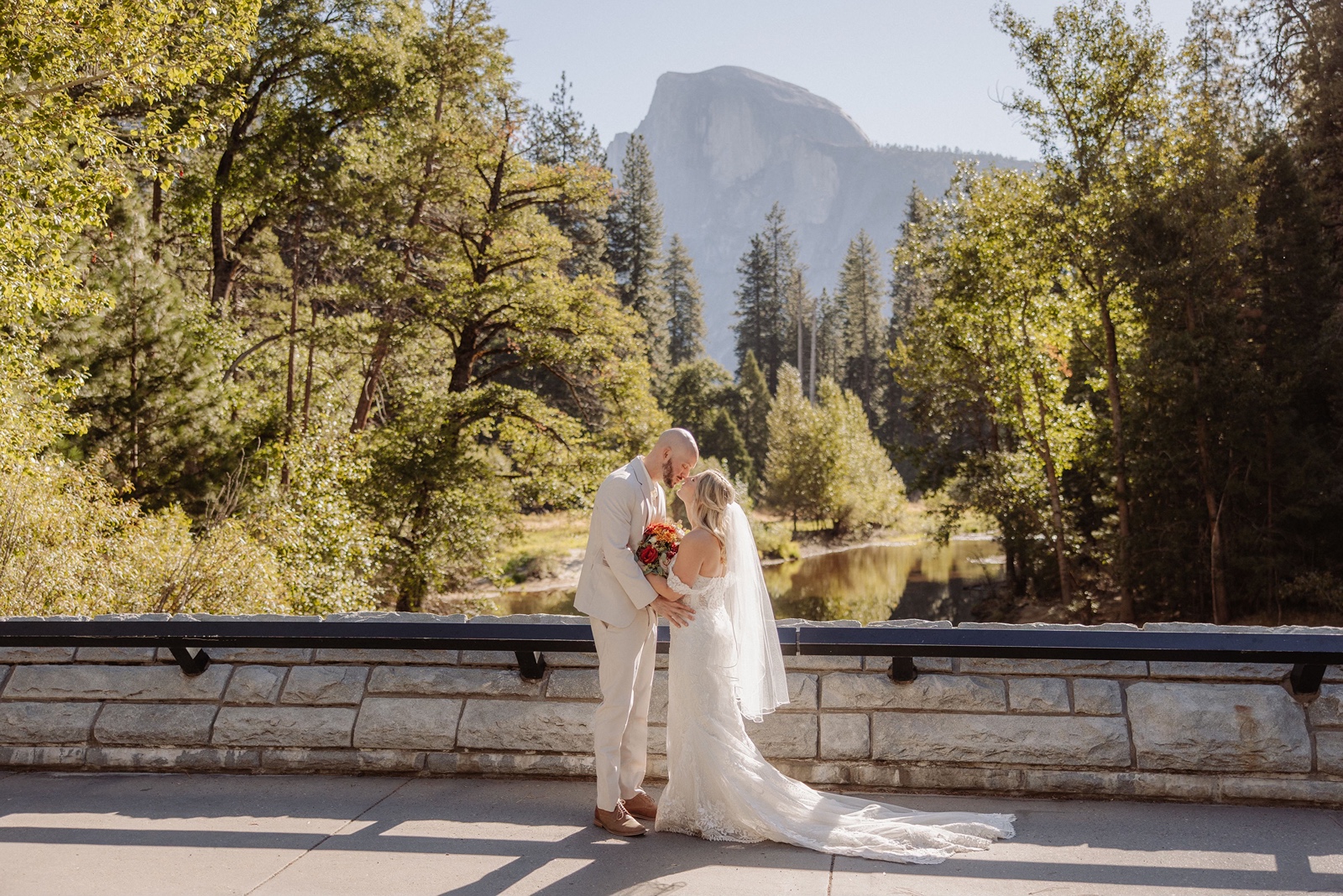 Bride and groom pose at Sentinel Bridge during their Yosemite elopement