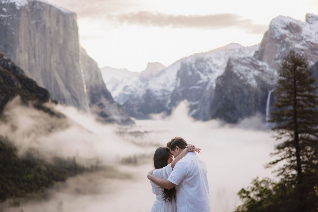 Man and woman hug during cloudy spring Yosemite engagement session
