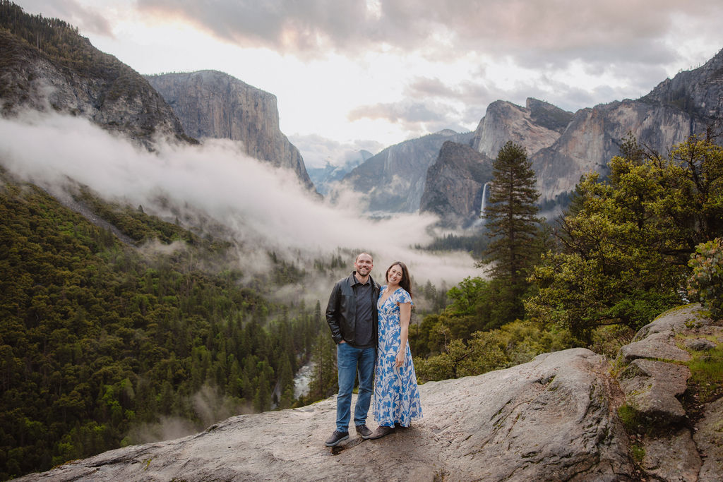 Man and woman smile at camera during spring Tunnel View engagement photos