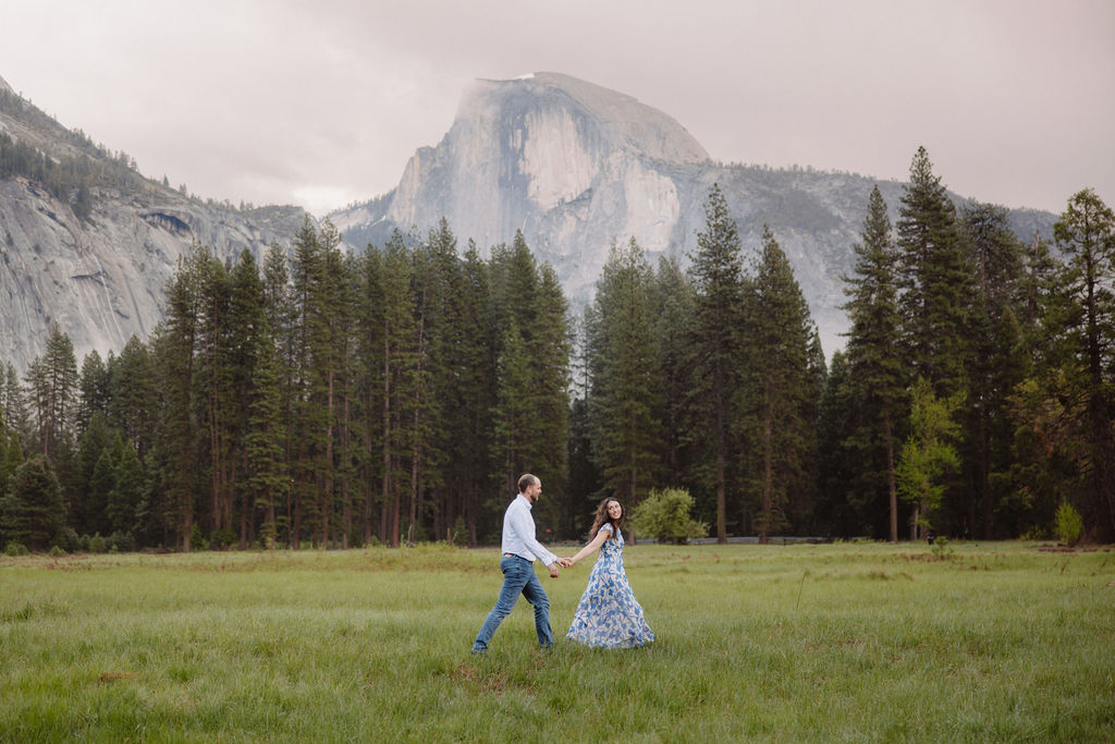 Man and woman walk through Yosemite Valley during engagement photos