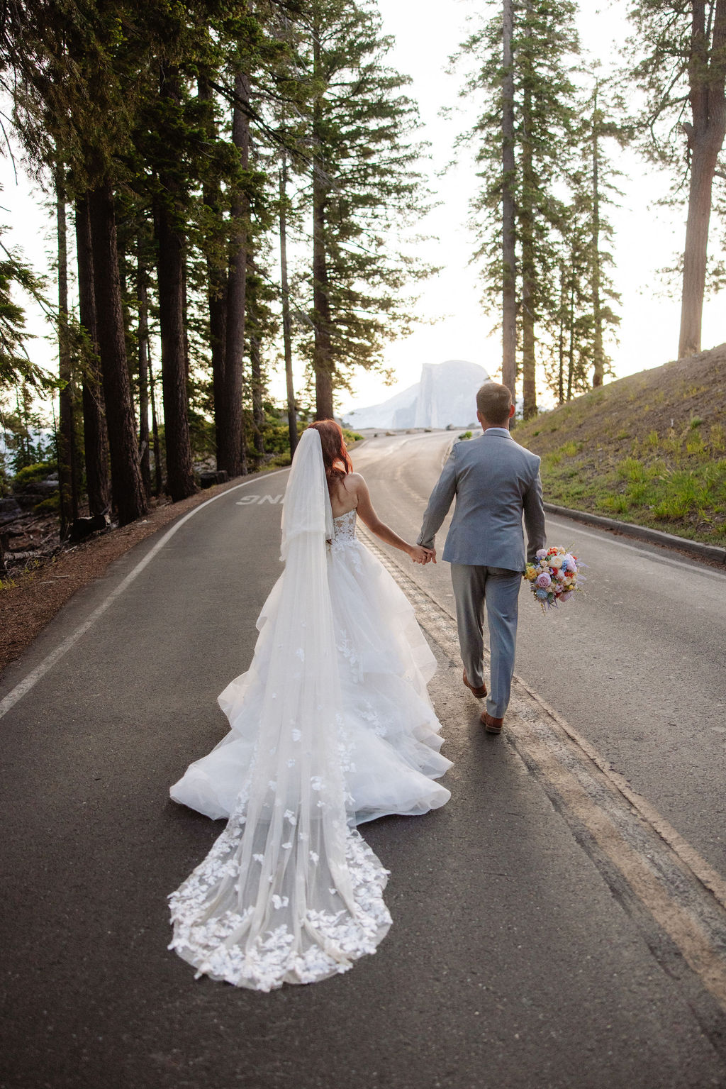 Couple walks holding hands before their sunrise Glacier Point elopement